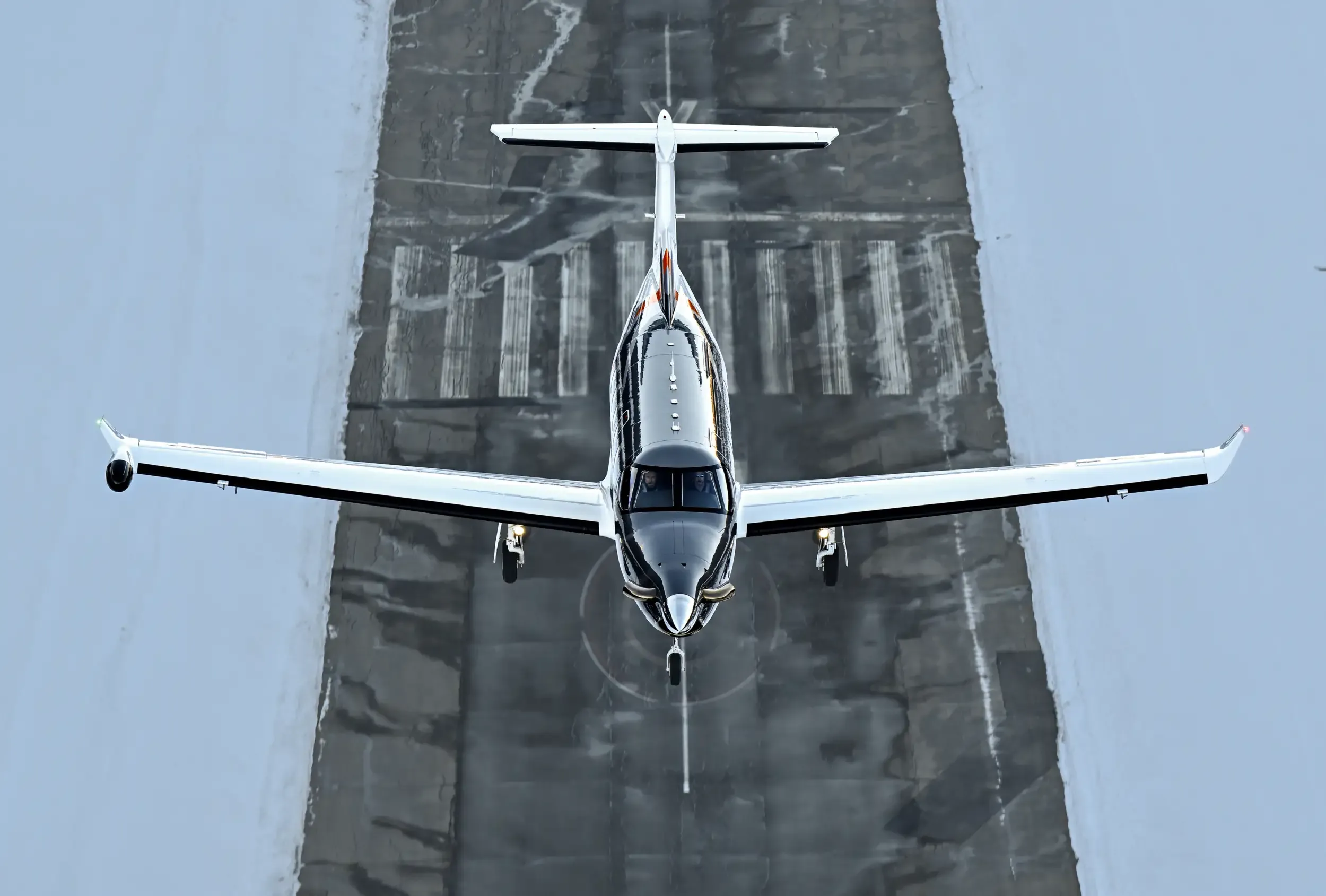 Overhead view of a Pilatus PC-24 aircraft on a snowy runway.