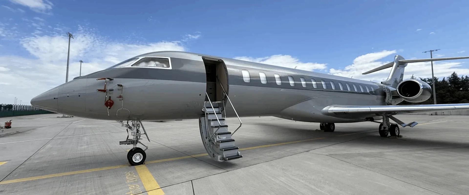 Grey and white aircraft on the tarmac with airstair door open.