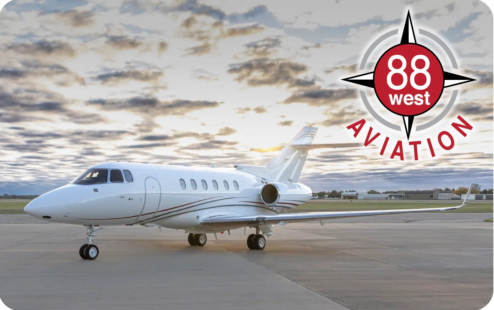 A white jet aircraft is parked on the tarmac with the 88 West Aviation logo.