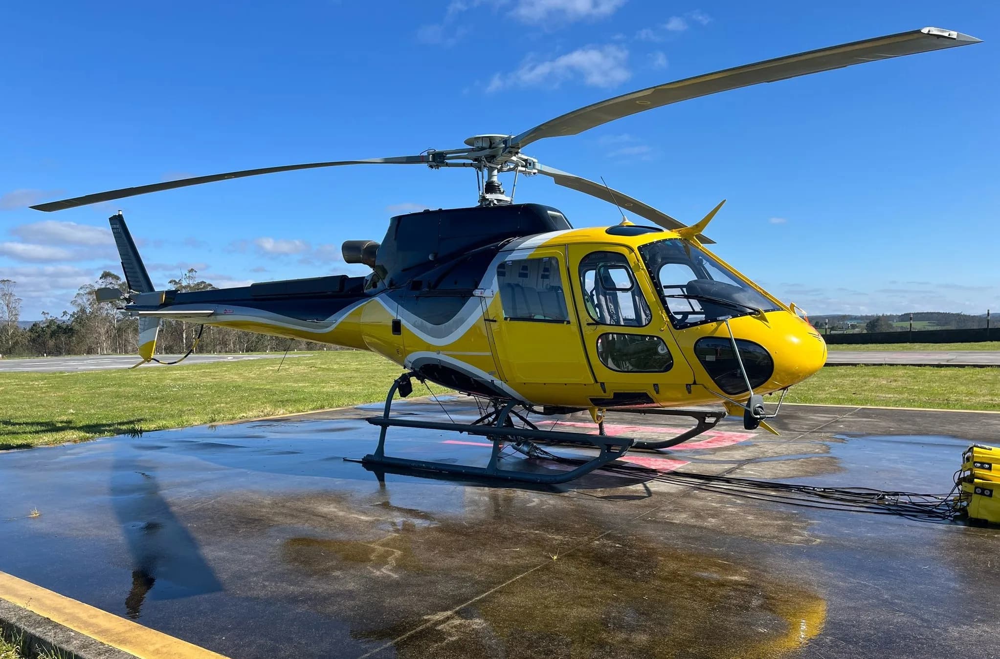 Yellow and black helicopter on a helipad.