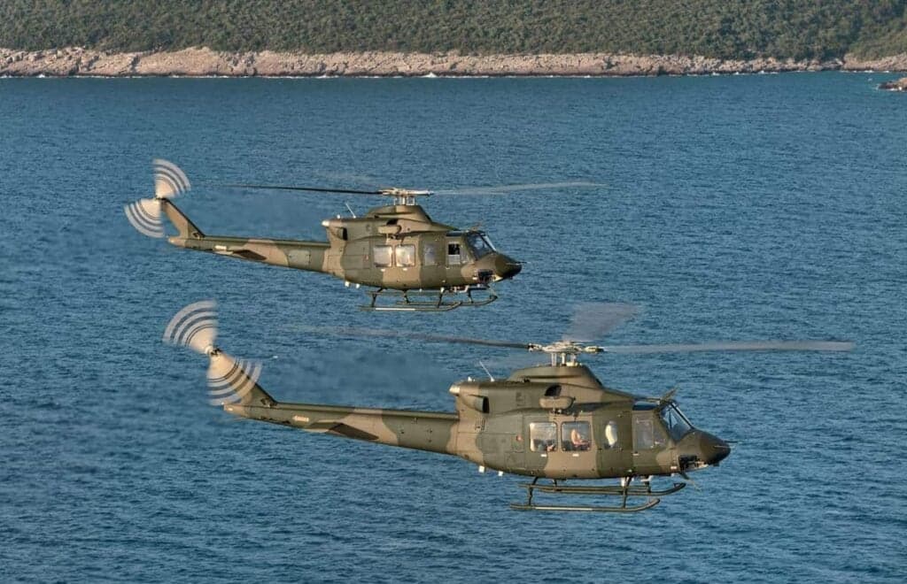 Two Bell UH-1 Iroquois helicopters flying over the ocean.