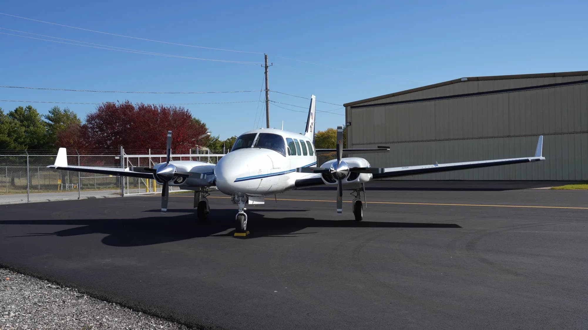 Front view of a white and blue twin-engine aircraft on the tarmac.