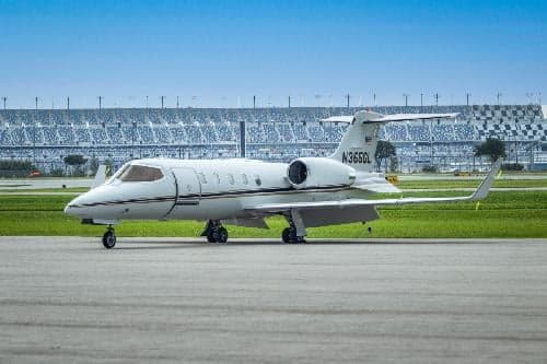 A Learjet 31A, registration N365GL, sits on the tarmac in front of a stadium.