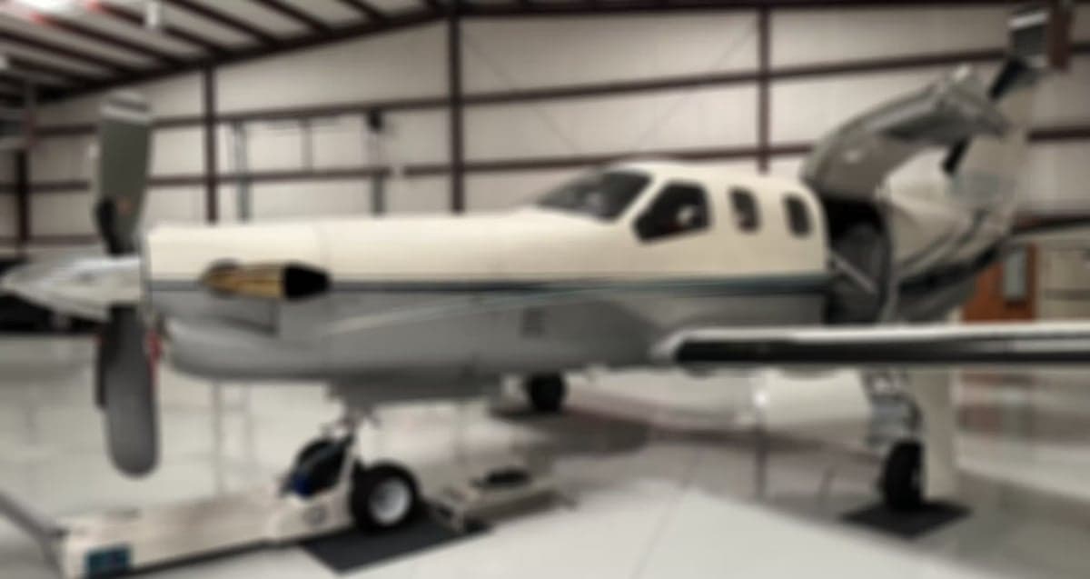 A blurred image of a turboprop aircraft in a hangar.