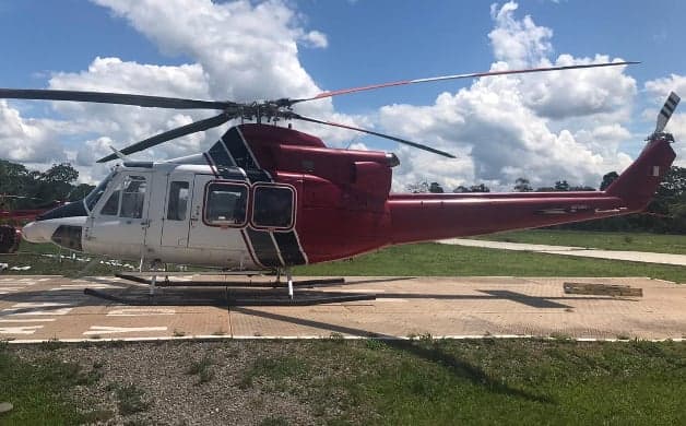Red and white Bell 212 helicopter on a helipad.