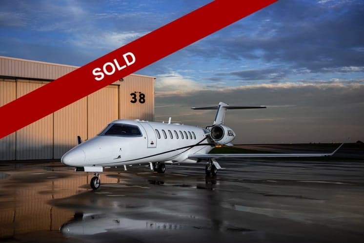 A Learjet 45XR aircraft with registration N26AL parked outside a hangar, with a SOLD banner overlay.