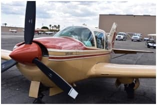 A tan and red single-engine aircraft, N44TL, parked on the tarmac.