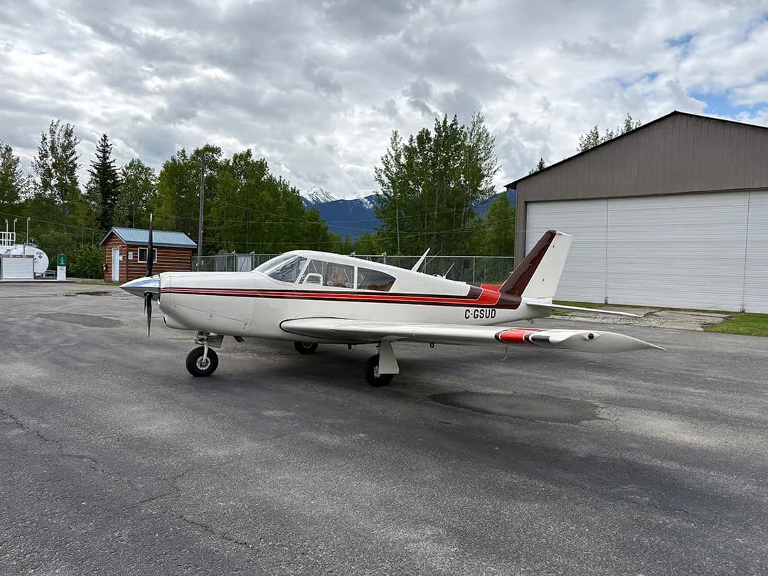 A white and brown aircraft with the registration C-GSUD parked on an airport tarmac.