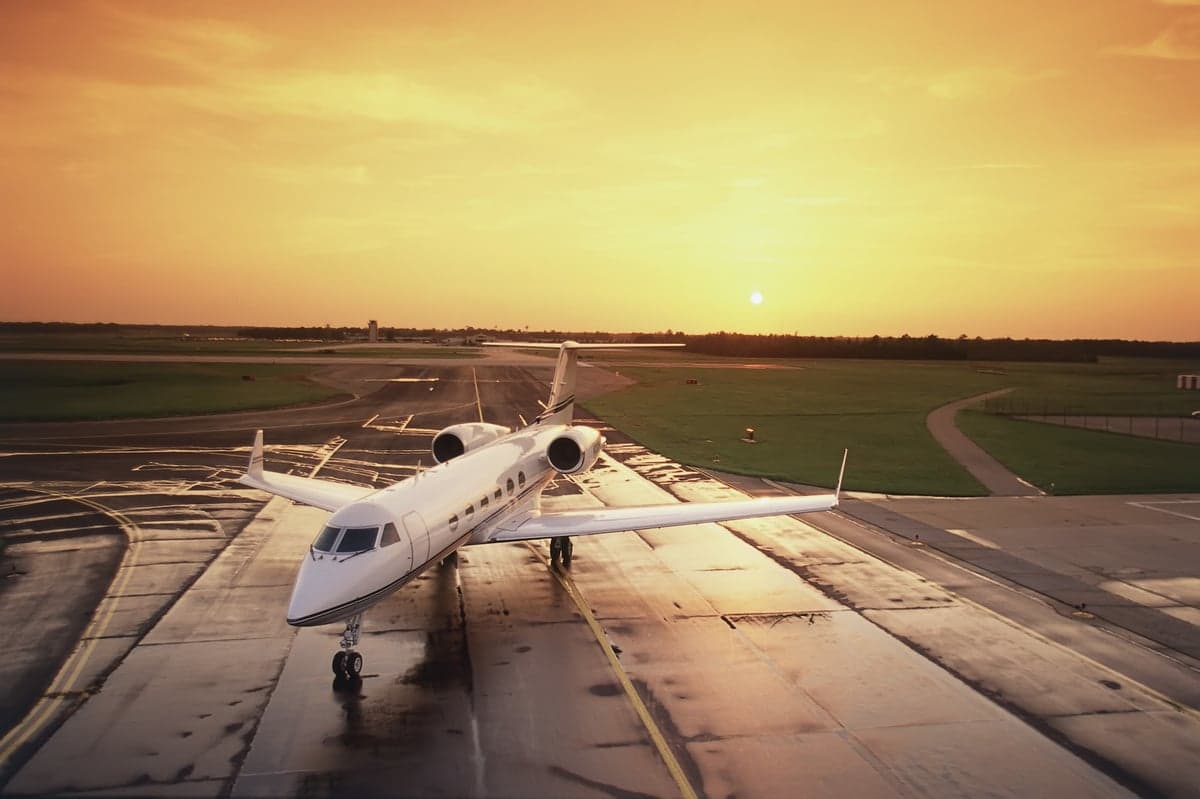 A Gulfstream G550 sits on the tarmac at sunset.