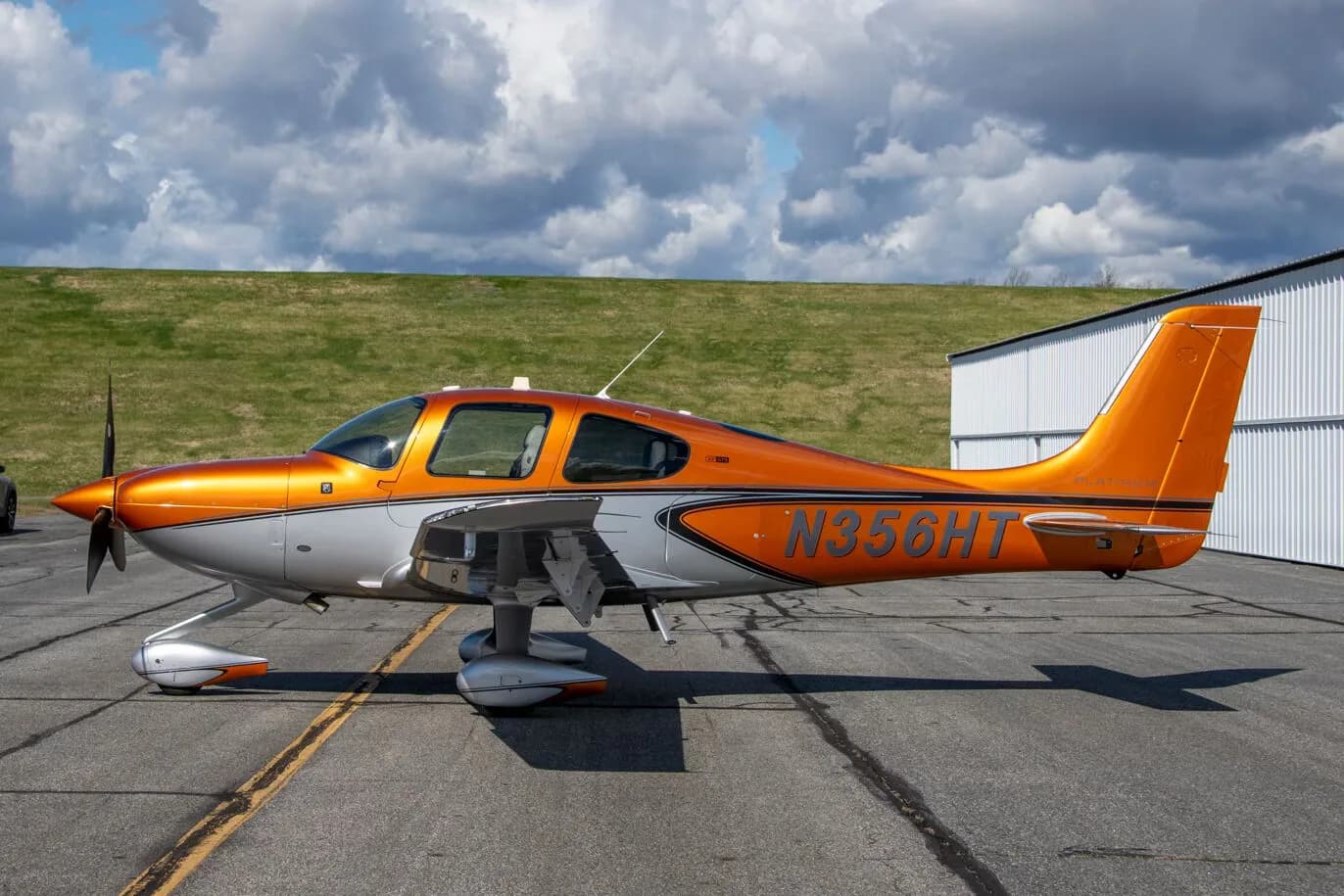 A side view of a metallic orange and silver Cirrus SR22 aircraft (N356HT) parked on an asphalt ramp.