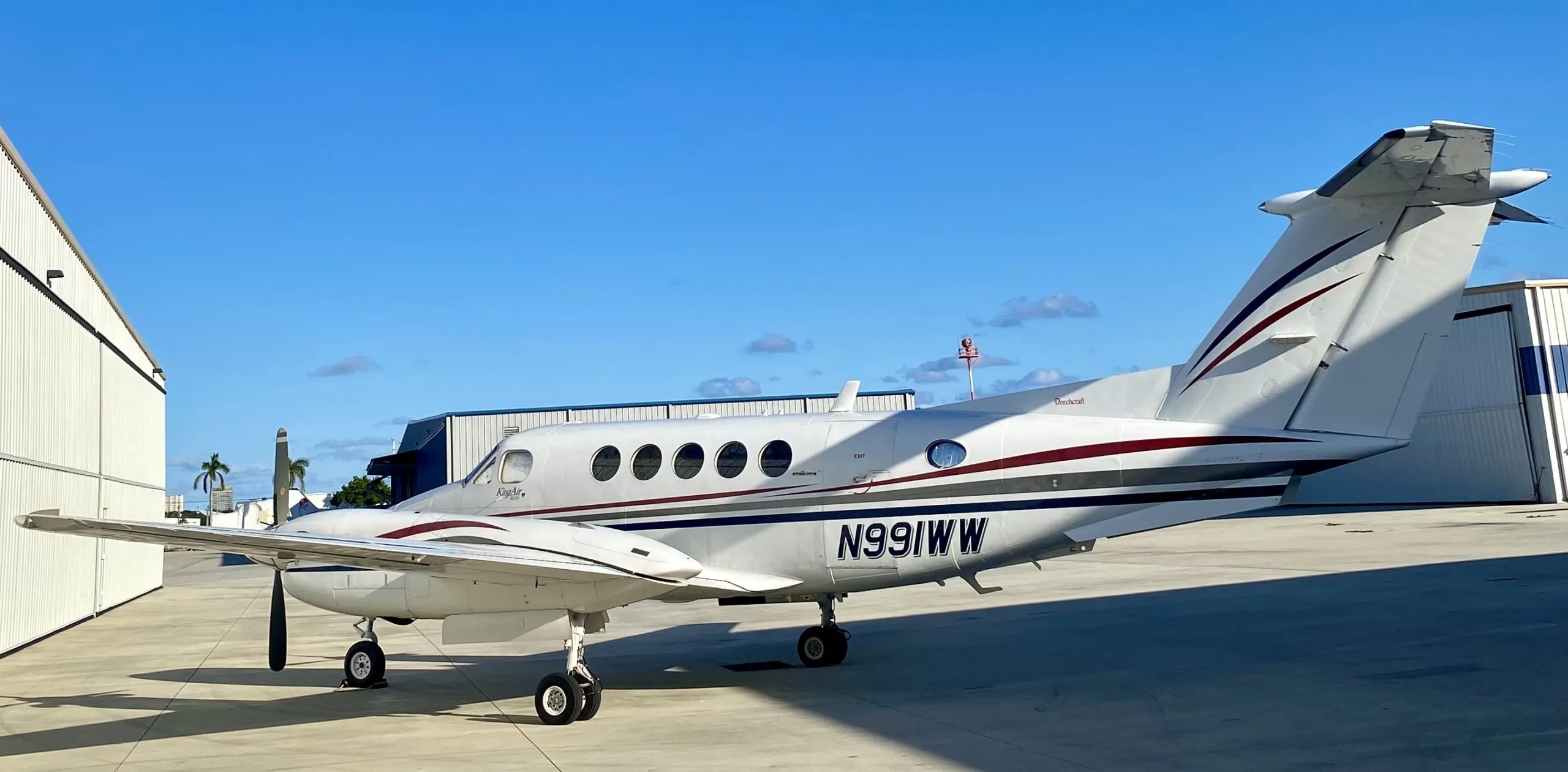 A Beechcraft King Air is parked on the tarmac with a white and maroon paint scheme.