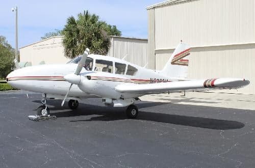 A white and brown striped Piper PA-28-181 Archer II is parked on the tarmac.