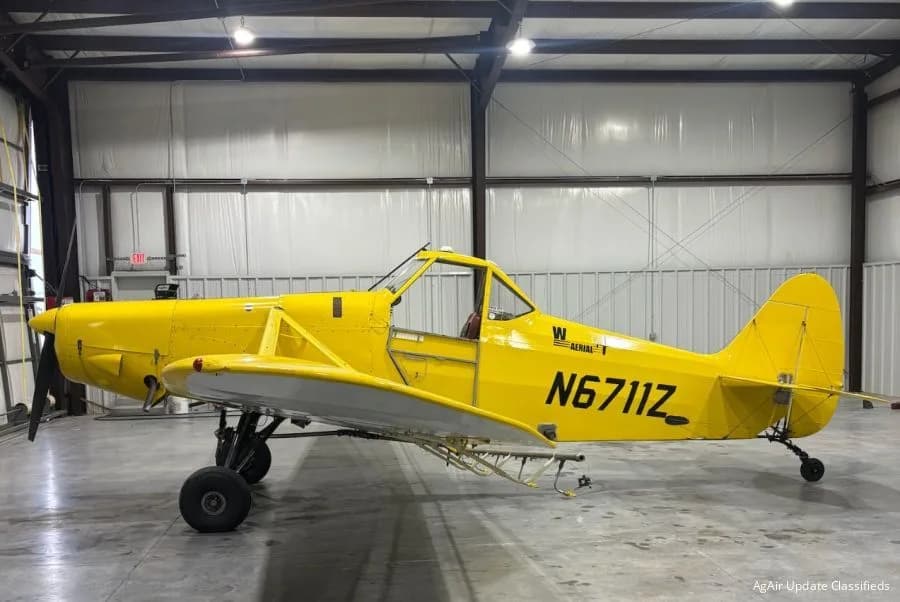A bright yellow agricultural aircraft, registration N6711Z, is parked inside a hangar, viewed from the side.
