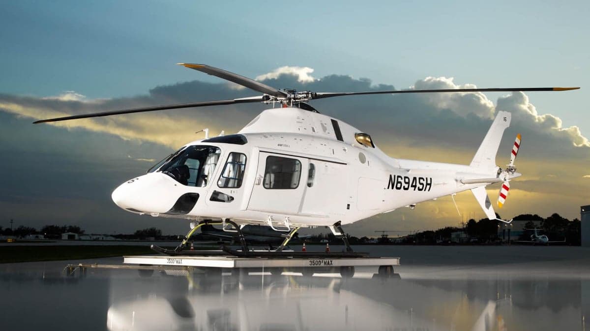 A white AgustaWestland AW119 Koala helicopter, registration N694SH, is parked on a platform at dusk.