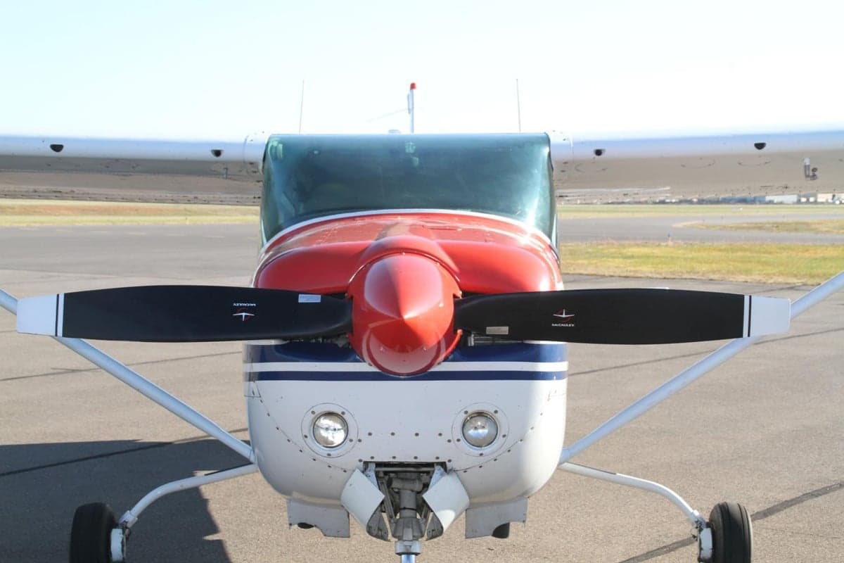Front view of the aircraft showing the propeller and red and white paint scheme.