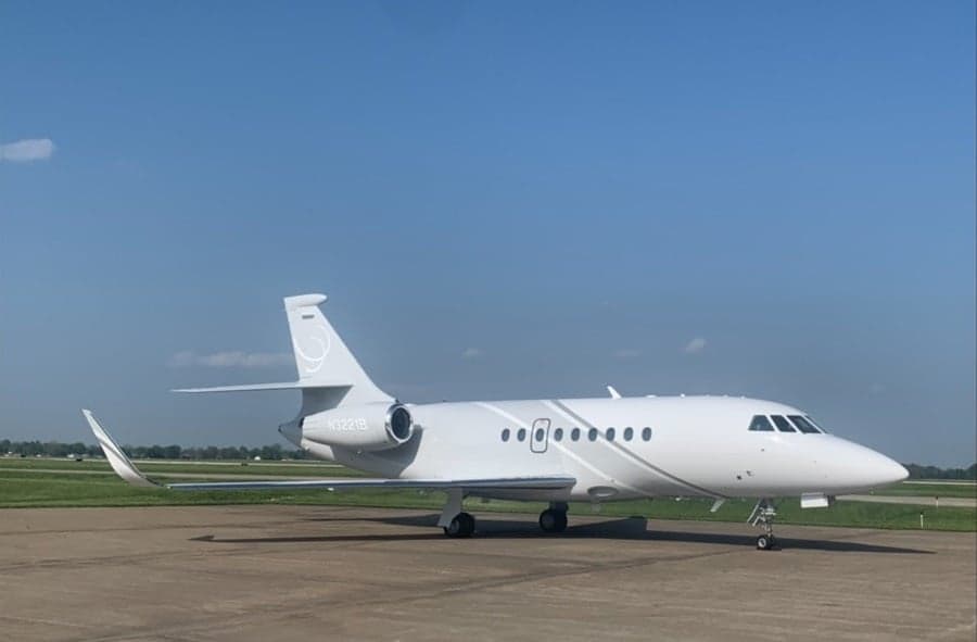 A Falcon aircraft is parked on the tarmac on a sunny day.