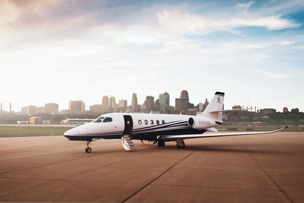 A Citation Latitude aircraft parked on the tarmac with the city skyline in the background.
