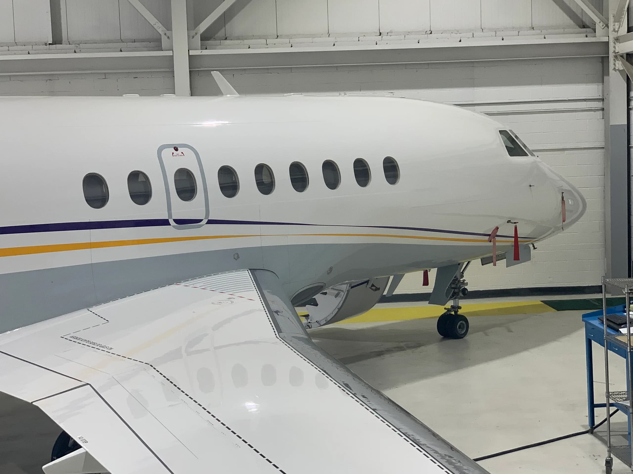 Close-up of the aircraft's nose and wing, showing the white paint scheme with blue and gold accents.