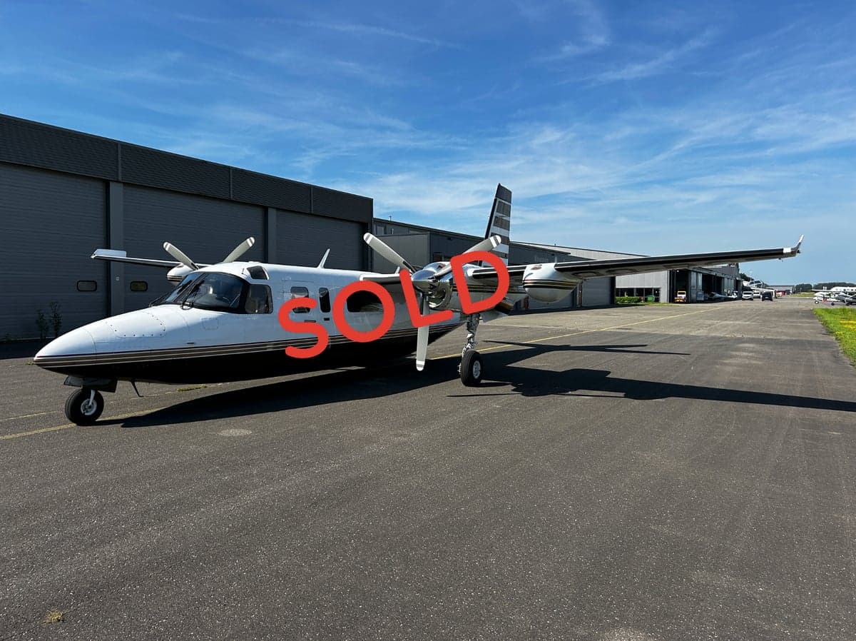 A twin-engine aircraft with a white and black paint scheme parked on the tarmac, marked with a 'SOLD' overlay.