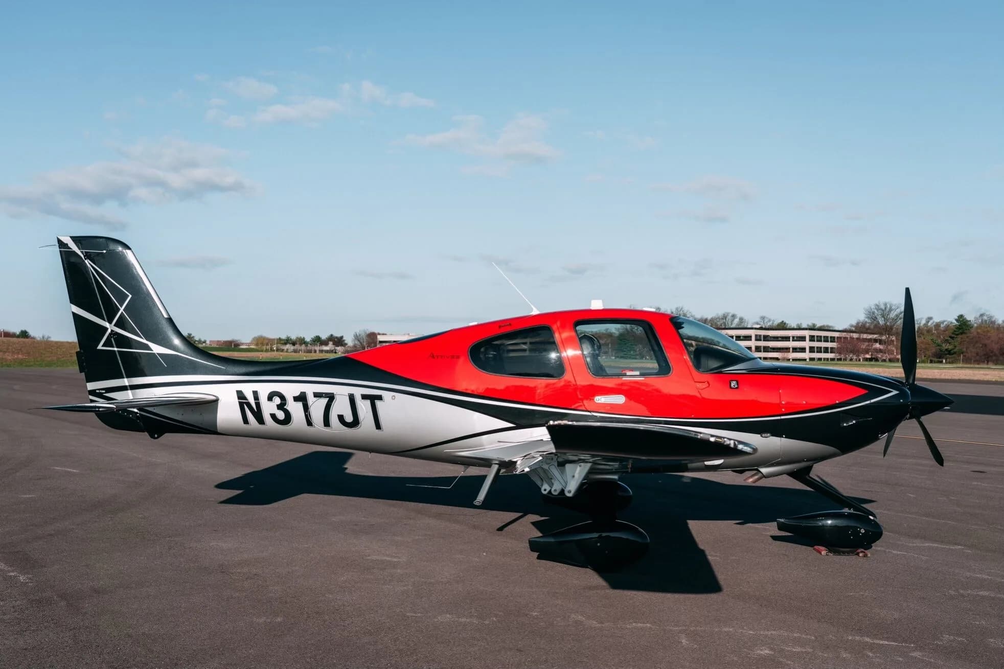 A red, black, and silver Cirrus SR22T aircraft (N317JT) parked on an asphalt tarmac.