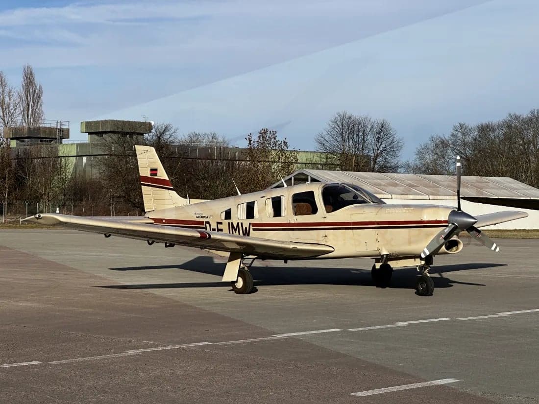 A Piper PA-28-181 Archer II, registration D-EJMW, parked on the tarmac.