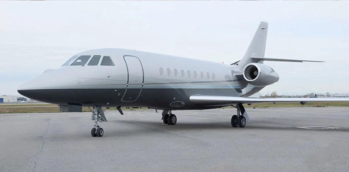 A silver and gray Falcon jet sits on the tarmac.