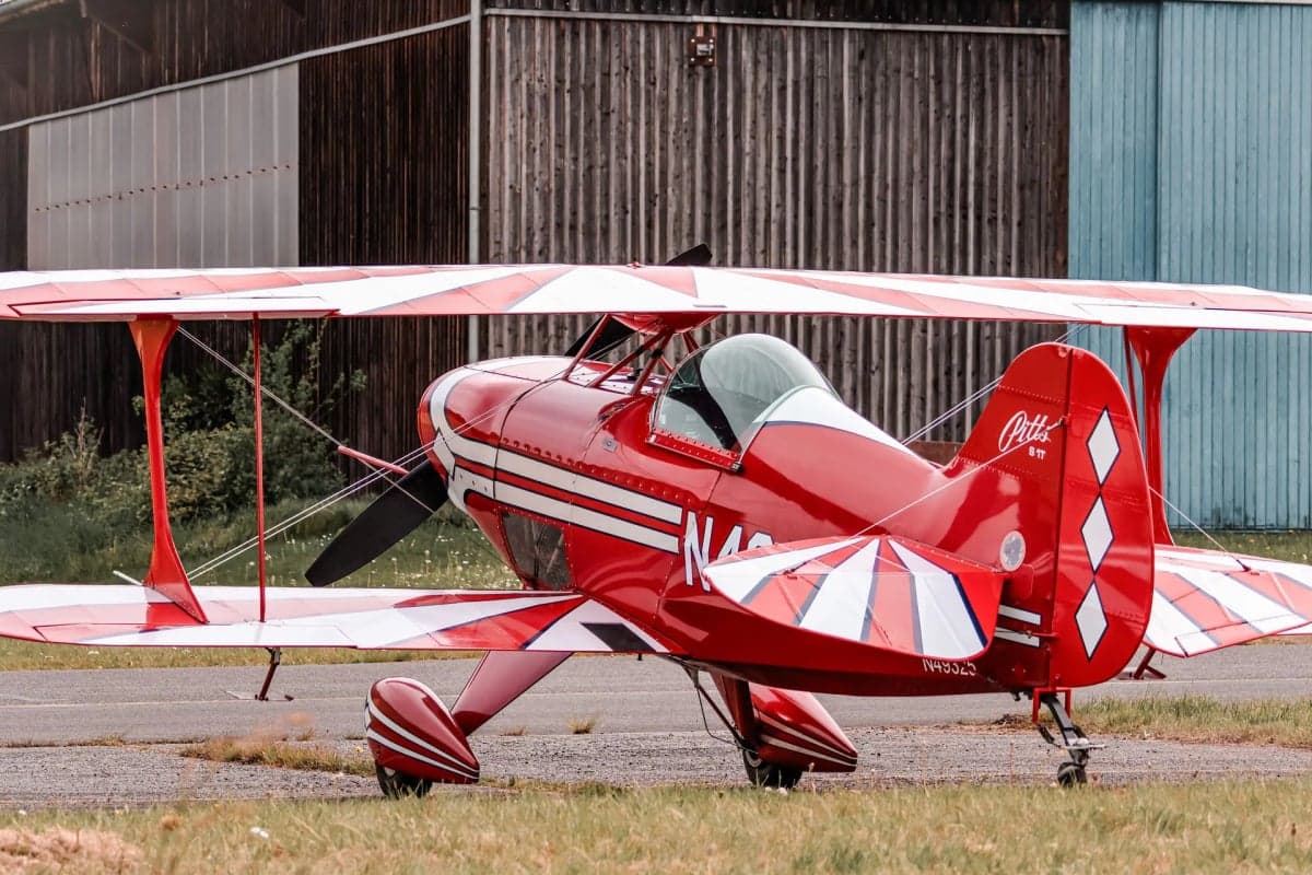 A red and white Pitts S-1T biplane with registration N49325 parked on the tarmac.