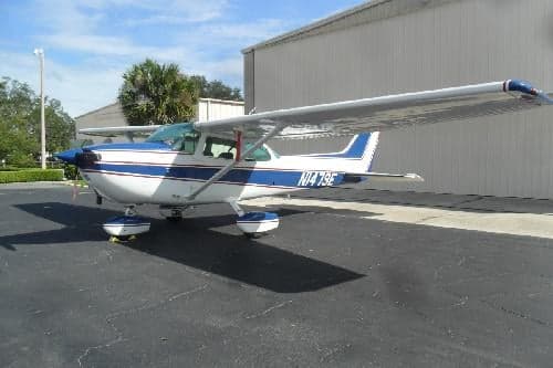 A white and blue Cessna 172 with tail number N1479E is parked on the tarmac.
