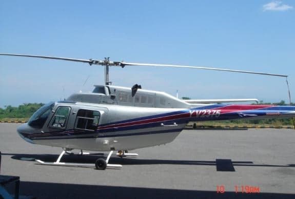 A silver and red helicopter sits on the tarmac.