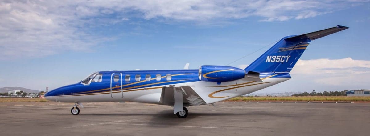 A Citation CJ2 aircraft with a blue and white paint scheme is parked on the tarmac.