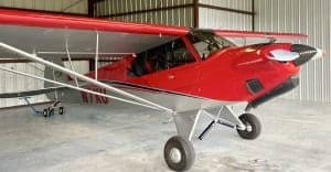 Close-up of the red and silver Carbon Cub N7XU inside a hangar.