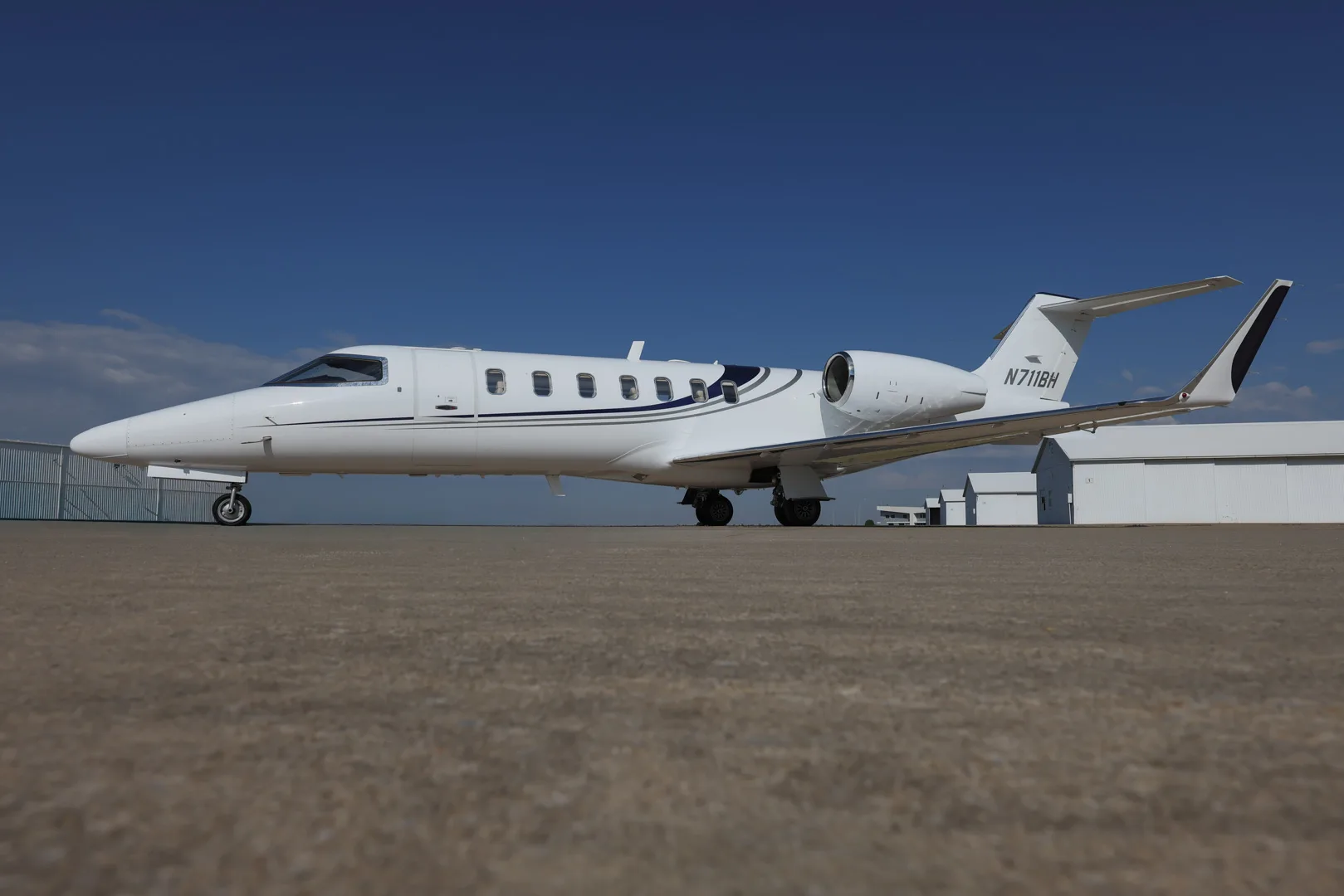 Side view of the white jet N711BH on the tarmac.