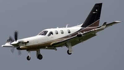 A TBM 900 aircraft in flight with landing gear down.