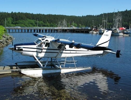 A de Havilland Beaver floatplane is docked in a harbor.