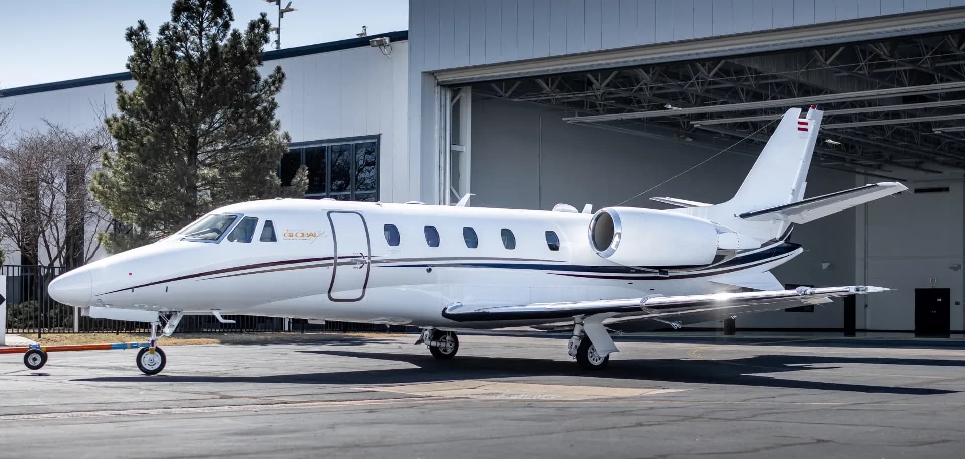 A white Global Express business jet is parked outside a hangar.