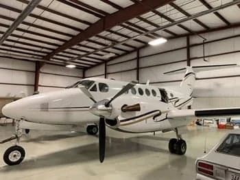 A Beechcraft King Air is parked inside a hangar.