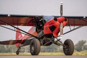 Front view of a red and black Carbon Cub aircraft on the ground.