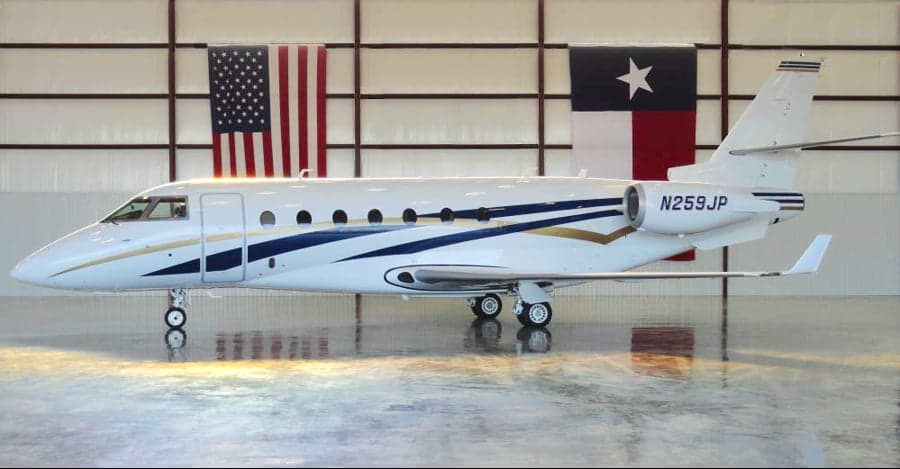 Gulfstream G280 aircraft N259JP in a hangar with American and Texas flags.