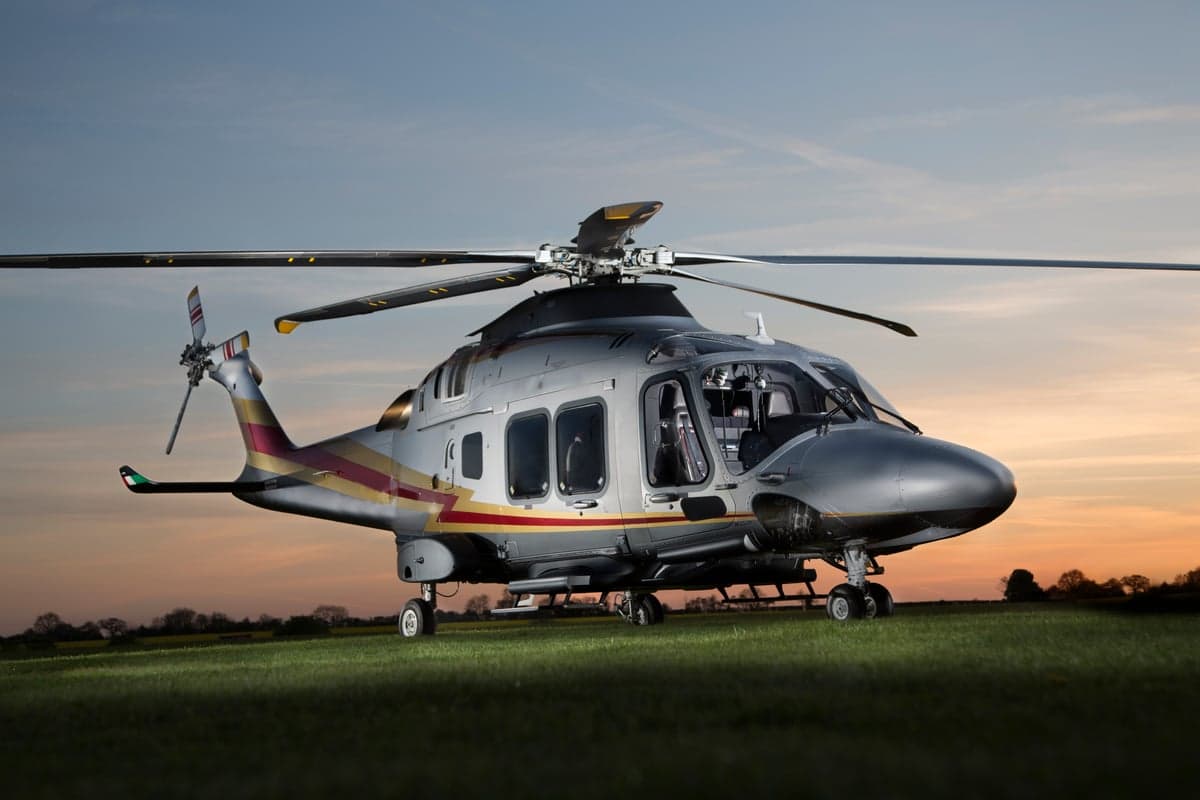 AgustaWestland AW169 helicopter taking off from a grassy field.
