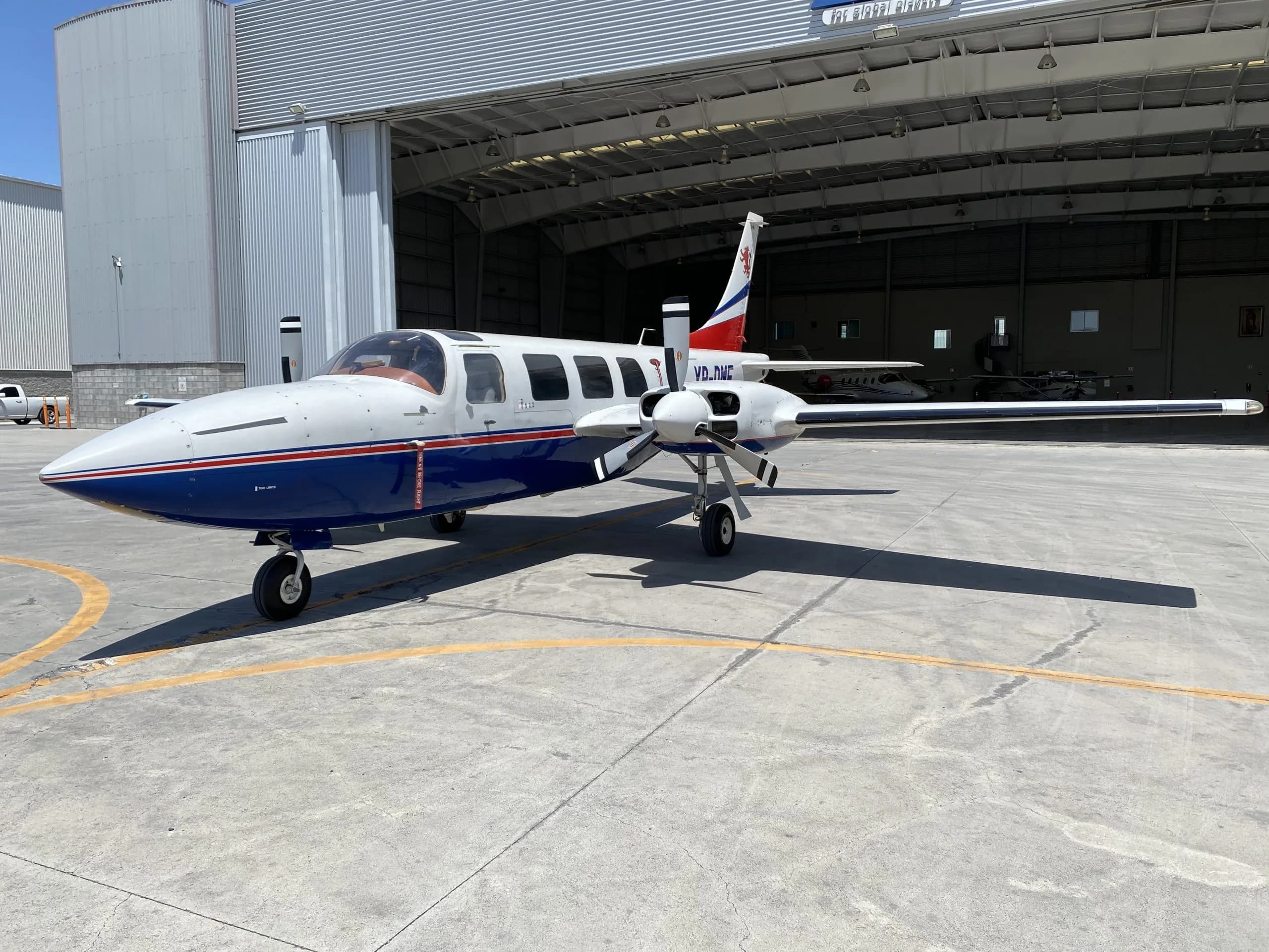 XB-DMF aircraft parked on the tarmac in front of a hangar.
