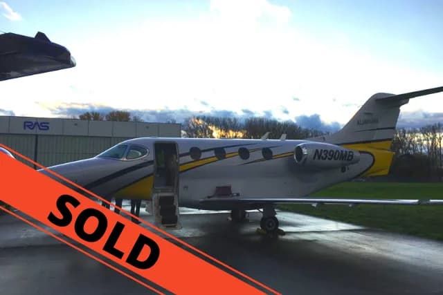 A silver and yellow light business jet, registration N390MB, parked on a tarmac with its door open, with a 'SOLD' banner overlaid.