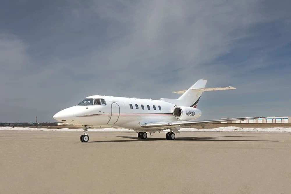 A Falcon 2000 aircraft with a white and red paint scheme is parked on the tarmac.
