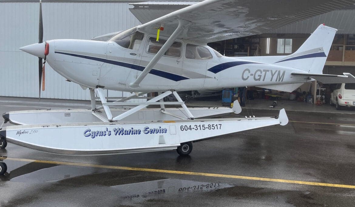 C-GTYM Cessna on floats, parked outside a hangar.