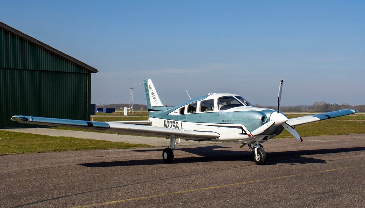 Piper Archer II aircraft N225SJ parked on the tarmac in front of a hangar.