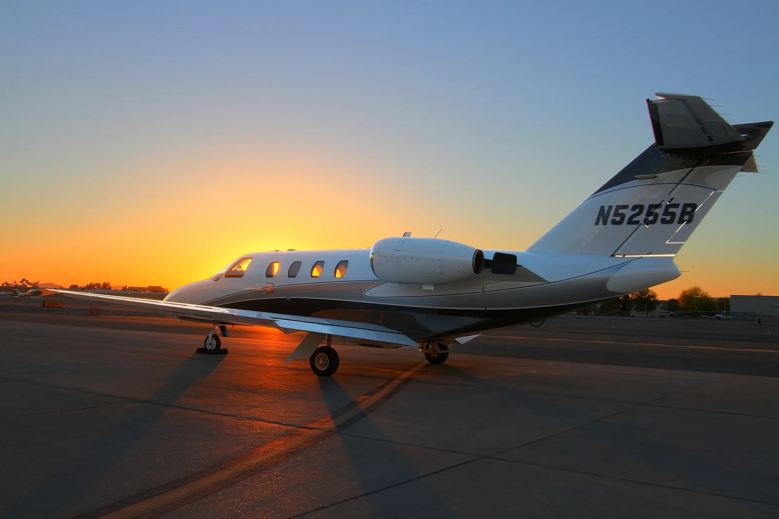 A Cessna Citation CJ3 aircraft with tail number N5255B is parked on the tarmac at sunset.