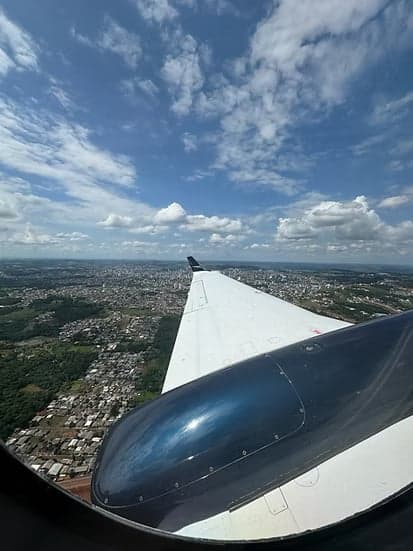 View of the aircraft wing in flight, with a city below.