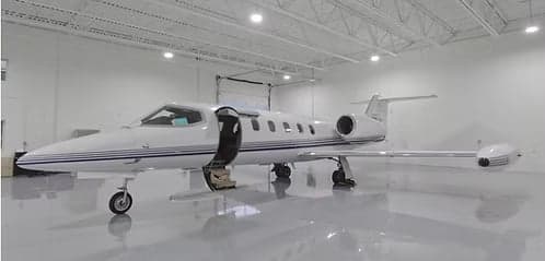 A Learjet with an open door inside a hangar.