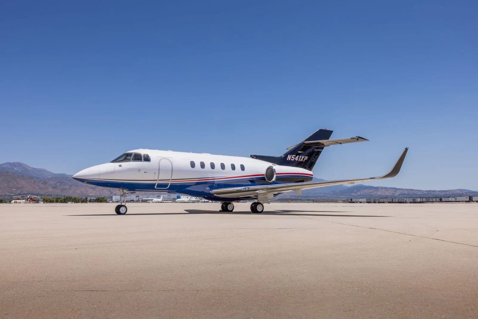 A Hawker 800XP business jet (N541XP) with blue and red stripes parked on a tarmac.