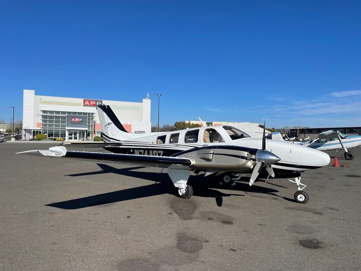 A Piper PA-31-350 Navajo Chieftain aircraft with a white and black paint scheme parked on the tarmac in front of a building.