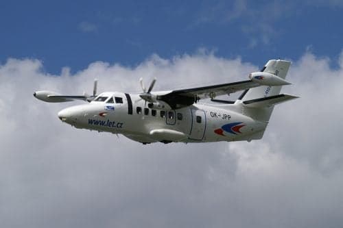 A Let L-410 Turbolet aircraft in flight against a cloudy sky.